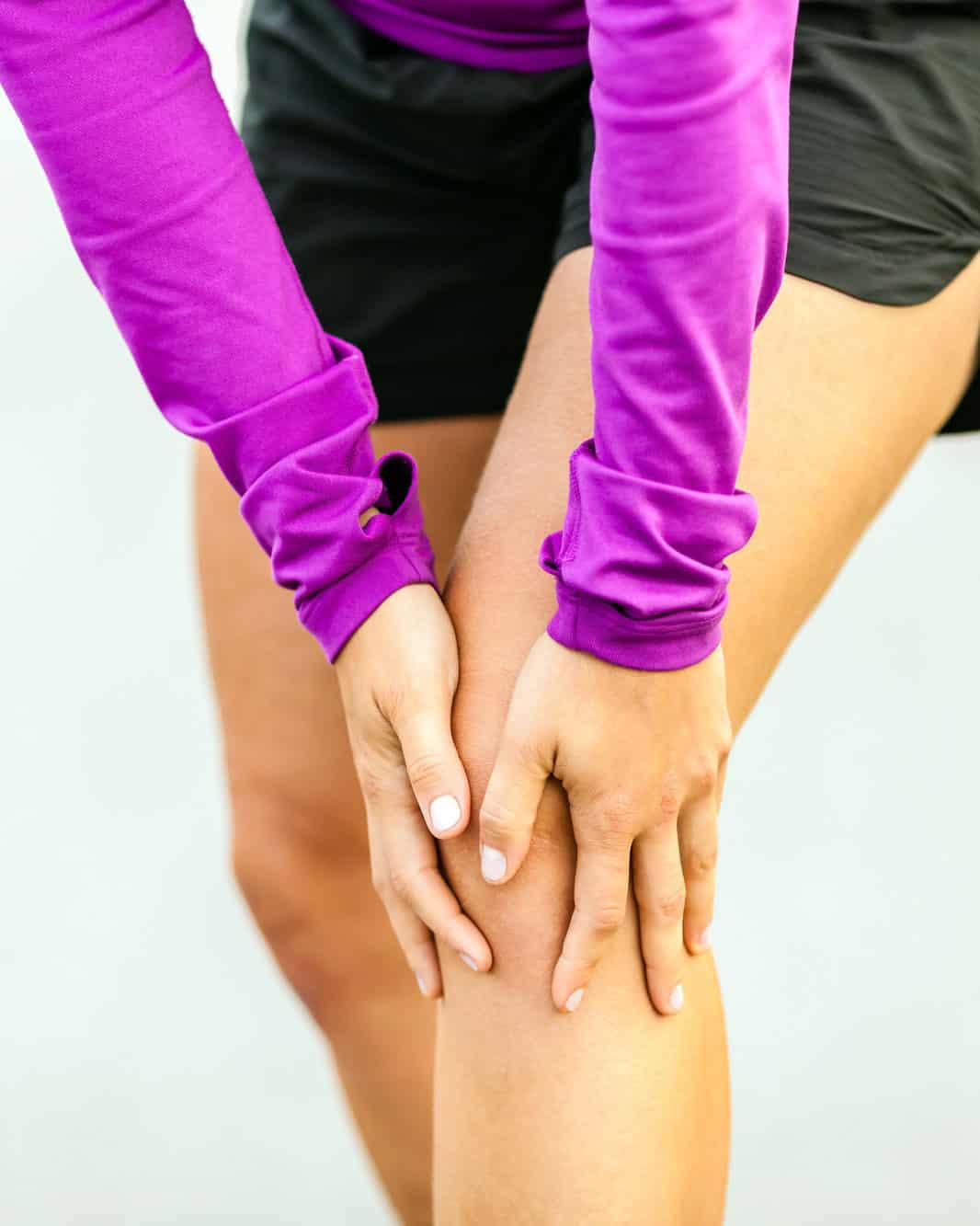 woman grabbing her knee in pain